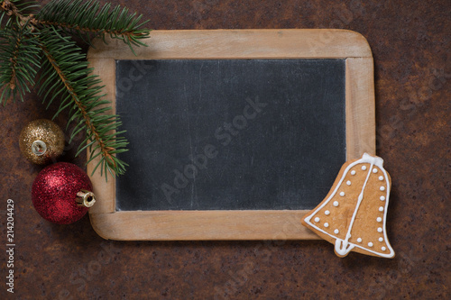 Christmas decoration. Blackboard and gingerbread Bell, spruce twig and Christmas tree balls. Empty space for text.