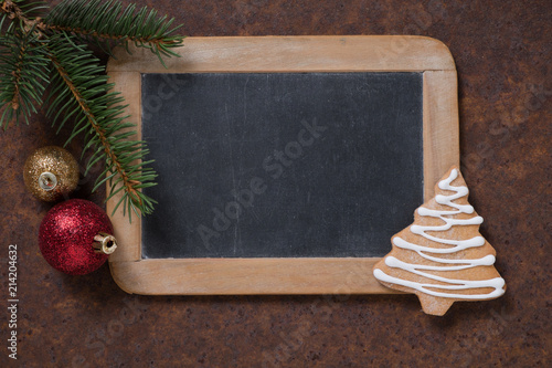 Christmas decoration. Blackboard and gingerbread Christmas tree, spruce twig and Christmas tree balls. Empty space for text.
