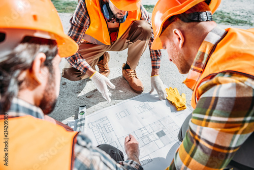 close-up shot of group of builders in hard hats having conversation about building plan photo