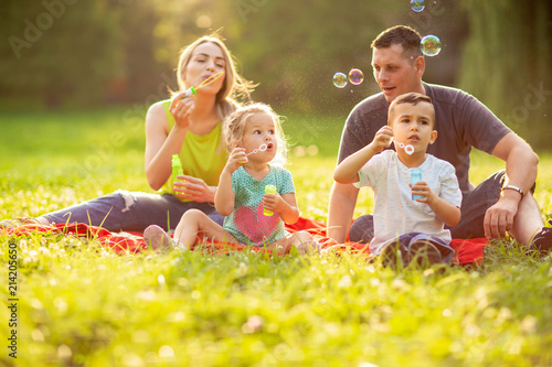 Family with children blow soap bubbles outdoor.