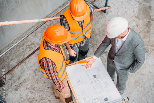 Wallpaper Mural high angle view of builders and architect discussing blueprint at construction s