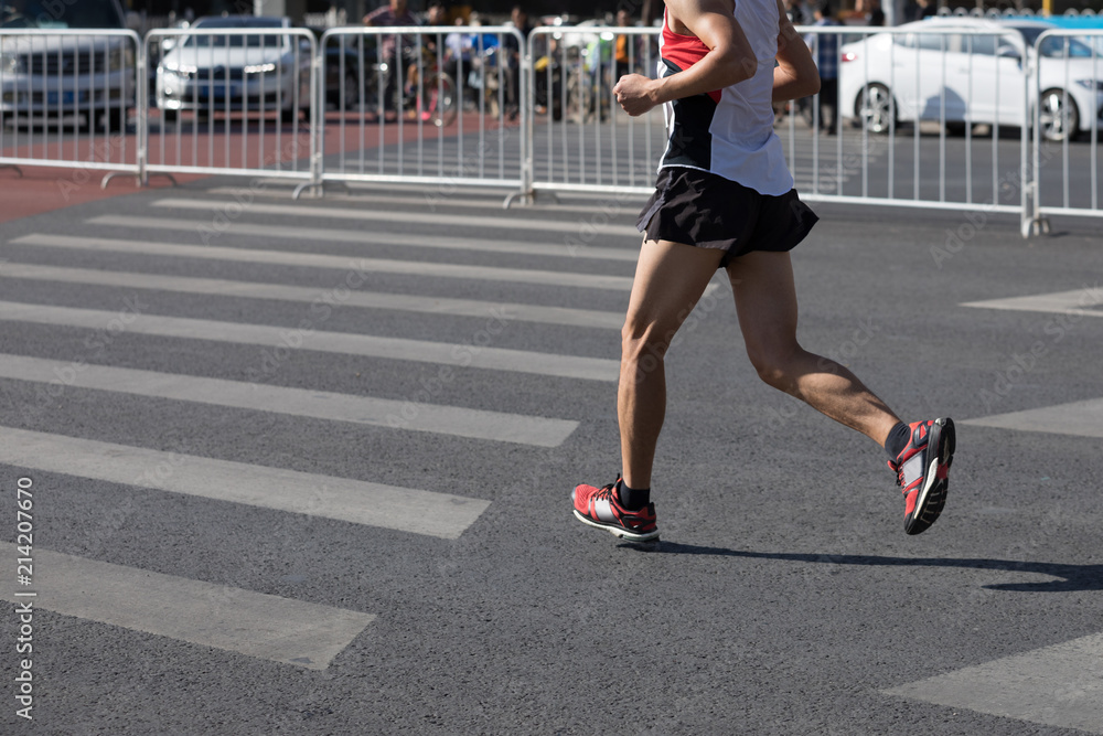 Legs of marathon runner running on city road