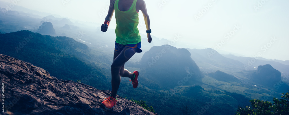 woman running on mountain top cliff edge - obrazy, fototapety, plakaty 
