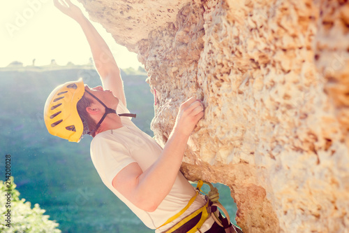 Canvas Print Picture of man in helmet clambering over rock up