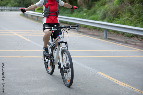 Woman cyclist riding bike with outstretched arms on road © lzf