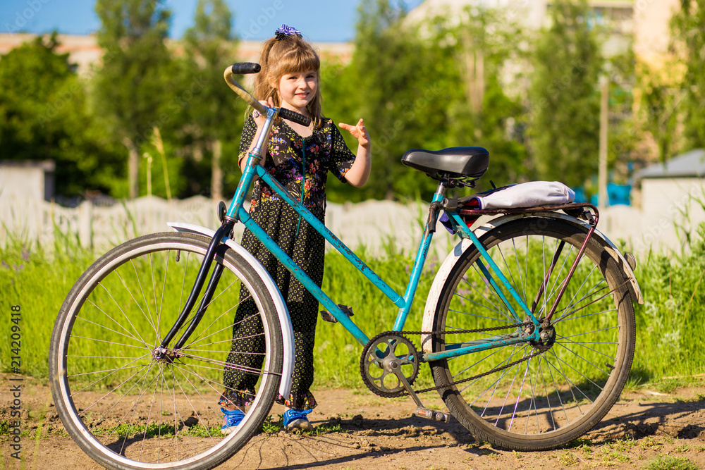Happy little girl riding big bicycle in city park Happy little girl riding big bicycle in city park