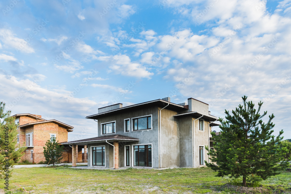 unfinished contemporary buildings with green yards on cloudy day with fir trees on foreground unfinished contemporary buildings with green yards on cloudy day with fir trees on foreground