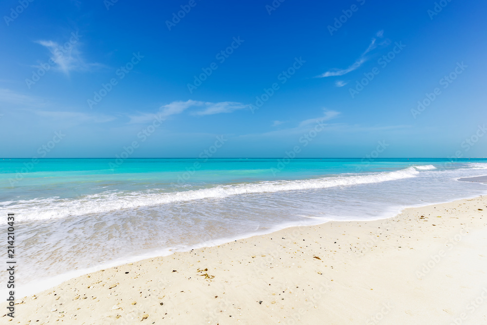 Wide tropical sandy beach in front of turquoise ocean