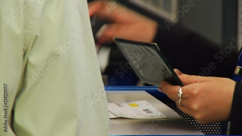 The airport employee carries out passport control of passengers going on board the aircraft. She looks at the passport and stamp the ticket