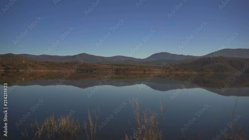 A beautiful blue lake with trees and reflections of mountains in the background. A beautiful blue lake with trees and reflections of mountains in the background.