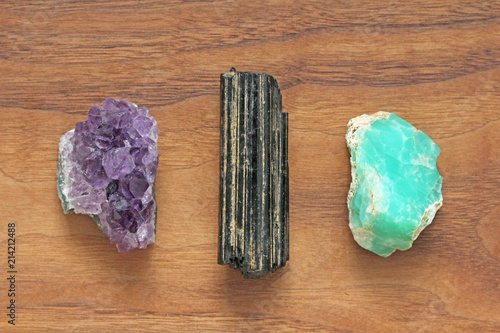Black tourmaline, Shirl, Amethyst, Chrysoprase. Collection of natural stones of minerals on a background of natural wood American black walnut. Beautiful untreated stones and minerals, crystals photo