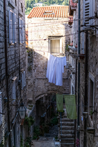 A typical street of the beautiful walled city of Dubrovnik, narrow and with slopes, also with drying sheets. Photograph taken in Dubrovnik, Dalmatia, Croatia.