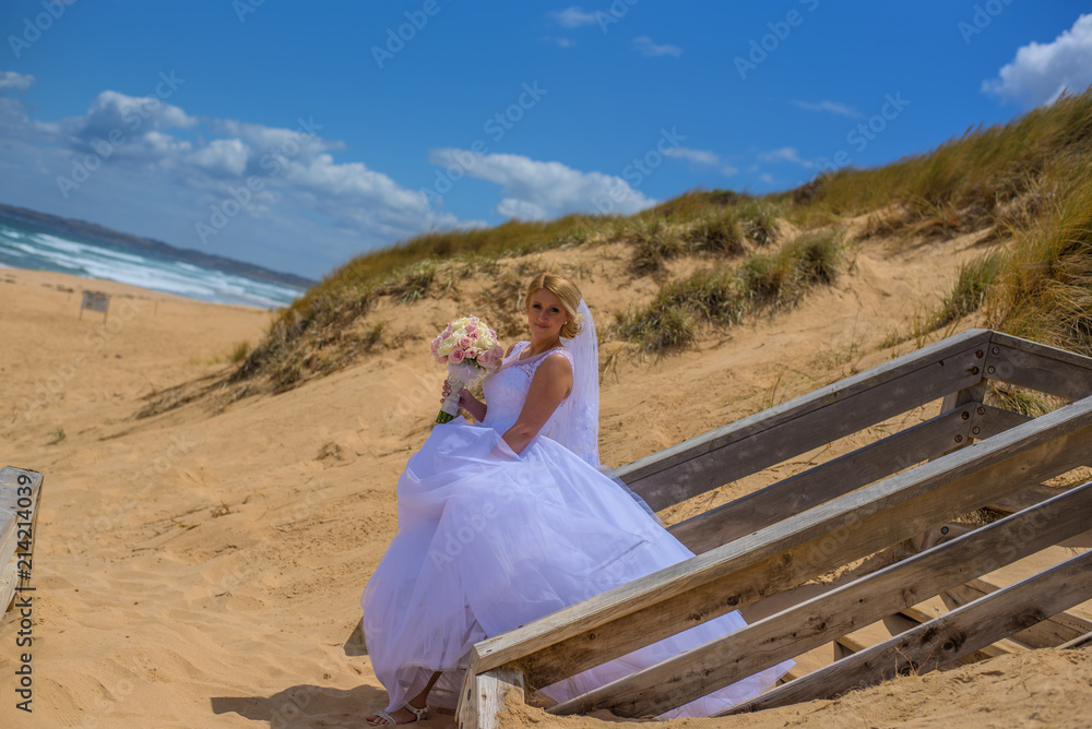 Bride in white wedding dress holding bouquet and posing at beautiful beach. Bride in white wedding dress holding bouquet and posing at beautiful beach.