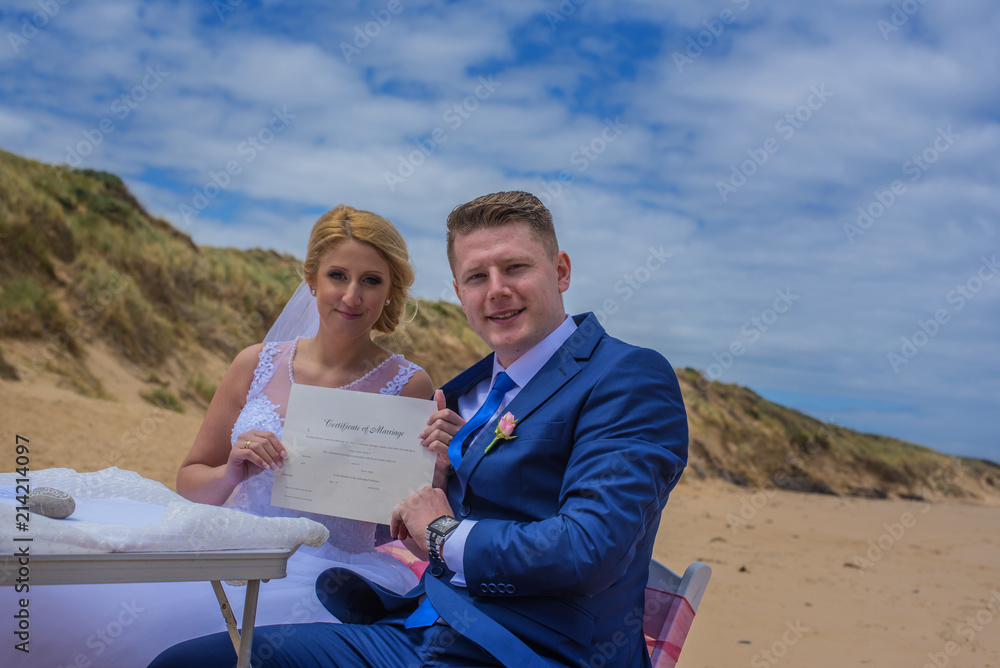 Just married couple holding certificate at beautiful Australian beach.
