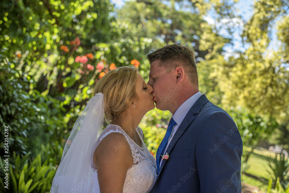 Just married couple wearing wedding dresses kissing in beautiful green garden. Shot at wedding in Australia on amazing sand beach. Just married couple wearing wedding dresses kissing in beautiful green garden. Shot at wedding in Australia on amazing sand beach.