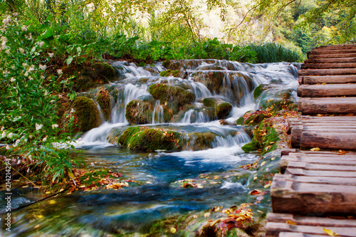 Small waterfall  water stream between rocks and grass