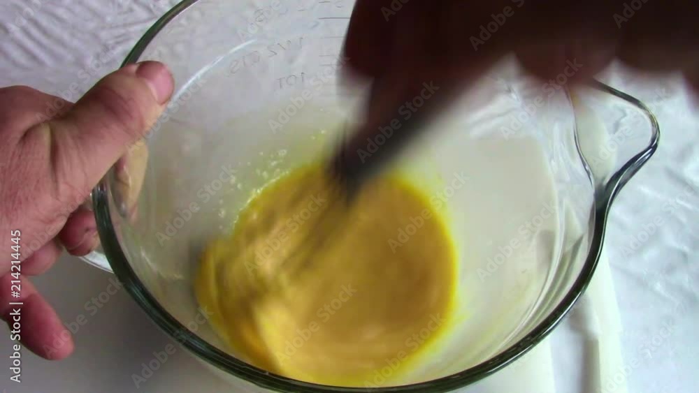Beating eggs in a glass jug with a metal whisk. Beating eggs in a glass jug with a metal whisk.