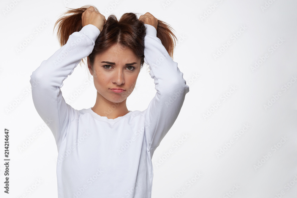 Portrait of playful funny teenage girl wearing blue shirt having fun indoors, holding hair in two tails, grimace as being unsatisfied, not getting what she wants.Human emotions and expressions concept Portrait of playful funny teenage girl wearing blue shirt having fun indoors, holding hair in two tails, grimace as being unsatisfied, not getting what she wants.Human emotions and expressions concept