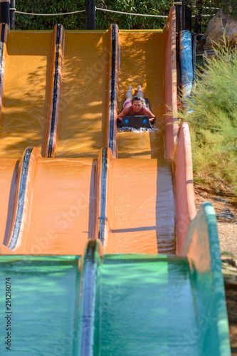 young woman ride on a slide in a water park