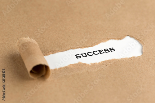 The text SUCCESS appearing behind torn brown paper