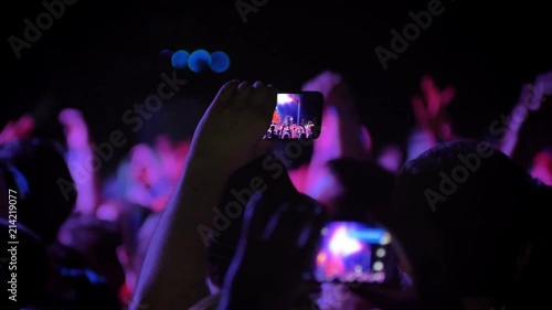 Man recording video at rock concert at night, standing in crowd