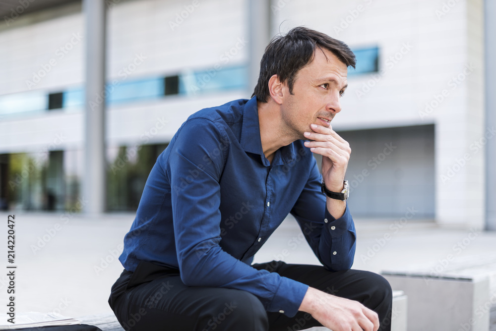 Businessman sitting outdoors thinking Businessman sitting outdoors thinking