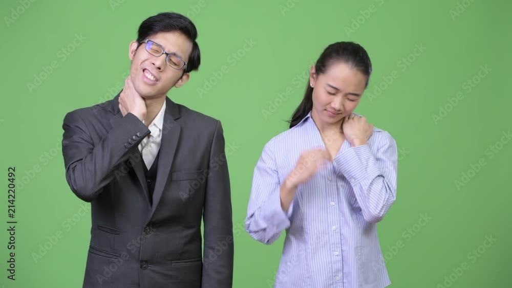 Young Asian business couple having neck pain together Young Asian business couple having neck pain together