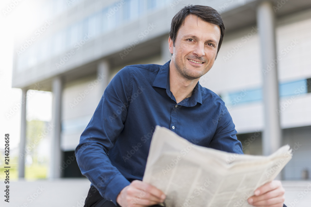 Portrait of smiling businessman with newspaper in the city Portrait of smiling businessman with newspaper in the city