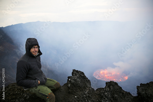 Africa, Democratic Republic of Congo, Virunga National Park, Man sitting over Nyiragongo volcano crater photo