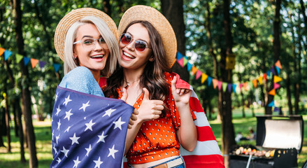portrait of happy women with american flag in park
