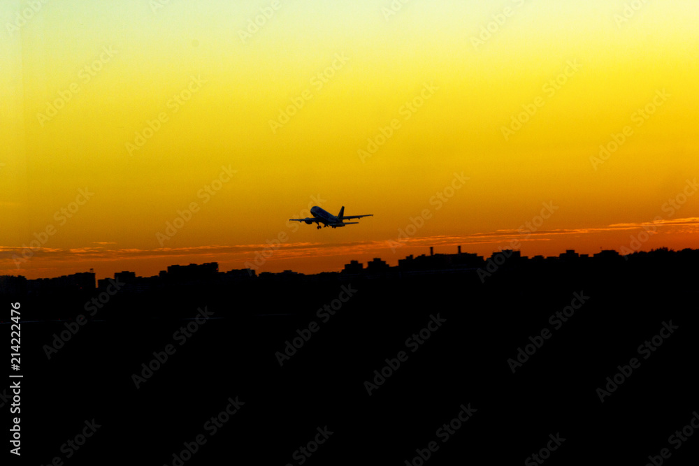 airplane take off at sunset yellow sun silhouettes of buildings