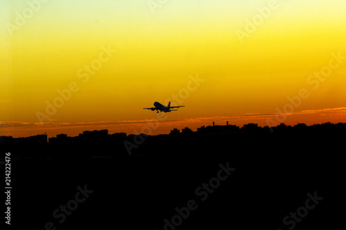 airplane take off at sunset yellow sun silhouettes of buildings