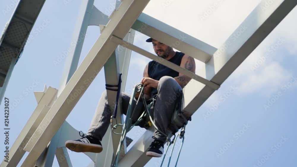 Guy sits on a bridge and raises a rope Guy sits on a bridge and raises a rope