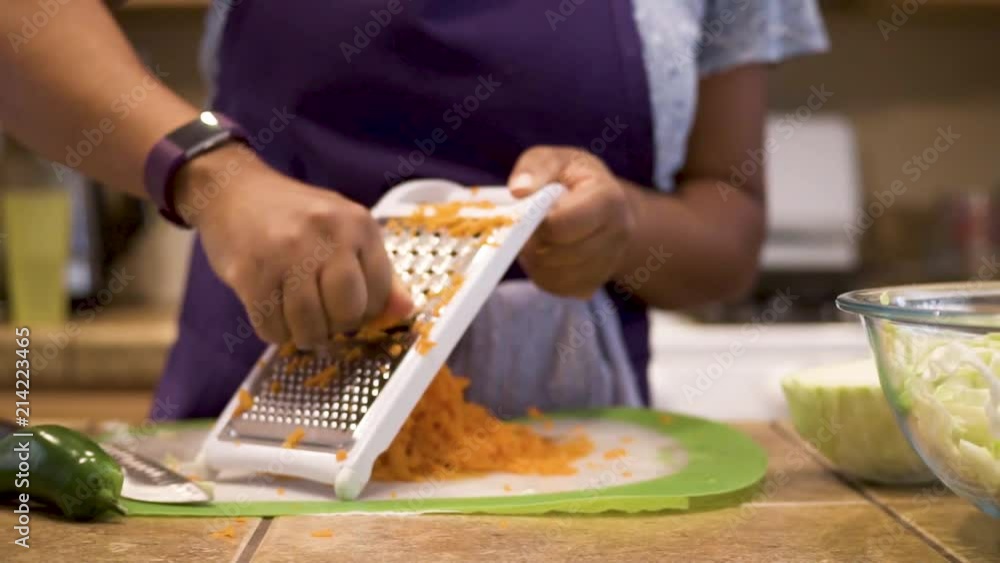 Woman grating carrots for a healthy recipe, Slowmo closeup pan right to left Woman grating carrots for a healthy recipe, Slowmo closeup pan right to left