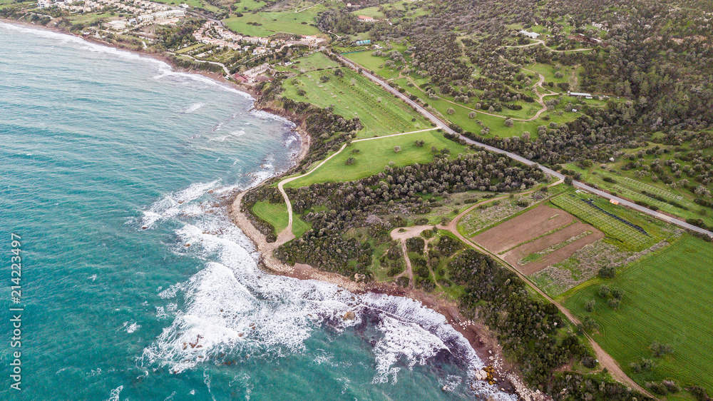 aerial view of foamy waves crashing on seashore with green grass and trees, Israel