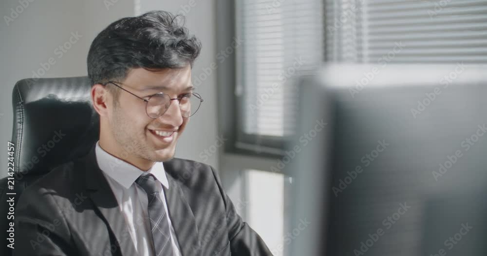 Young positive turkish businessman working at his computer on project and smiling, business concept 4k Young positive turkish businessman working at his computer on project and smiling, business concept 4k