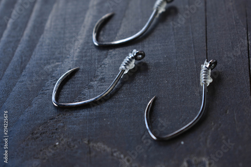 Metal fishing hooks on a black wooden table in a camp near river.