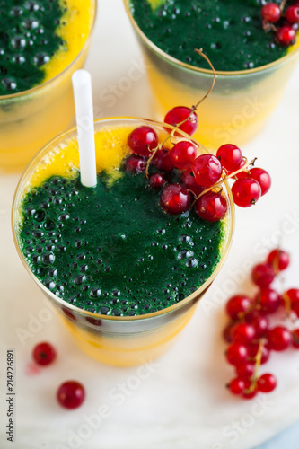 two colored fresh smoothies in glasses with fresh berries. orange banana juice with spirulina powder. detox breakfast. healthy eating photo