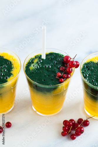 two colored fresh smoothies in glasses with fresh berries. orange banana juice with spirulina powder. detox breakfast. healthy eating photo