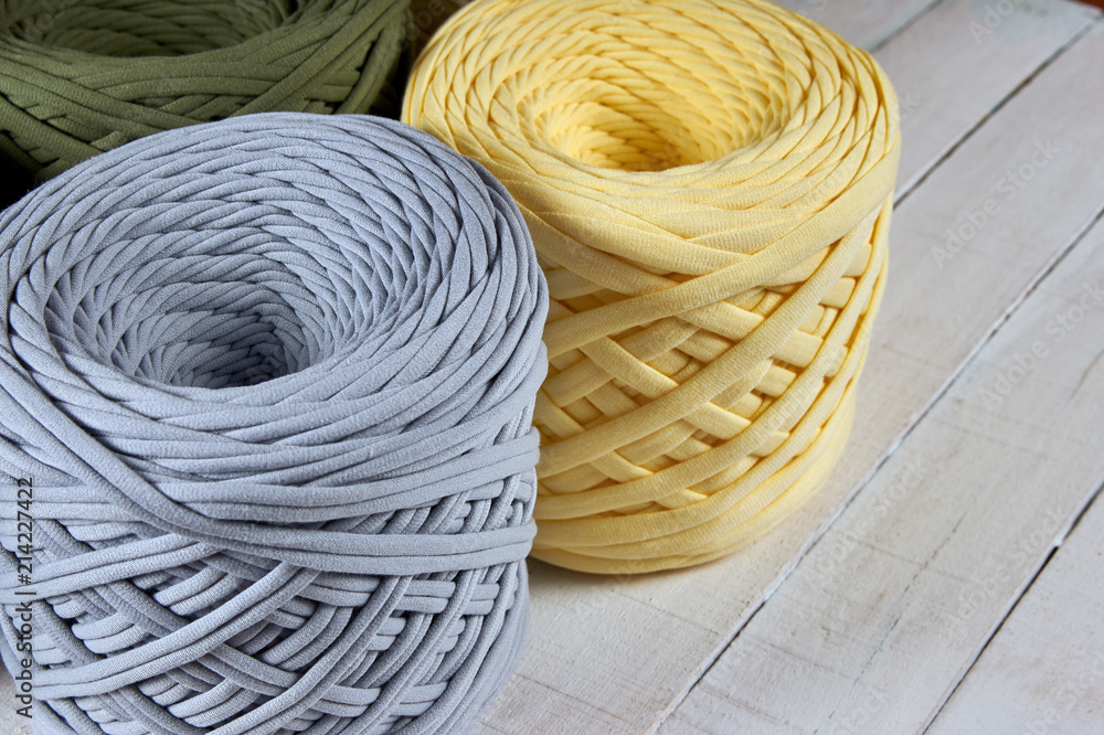 coils of colored knitted yarn on a white wooden background coils of colored knitted yarn on a white wooden background