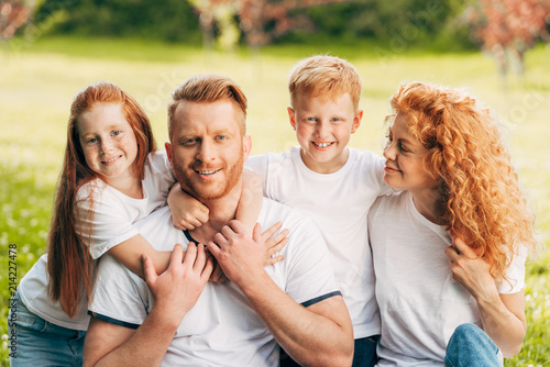 Φωτογραφία beautiful happy redhead family hugging and smiling at camera in park