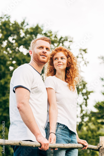 low angle view of happy redhead couple standing together and looking away at park
