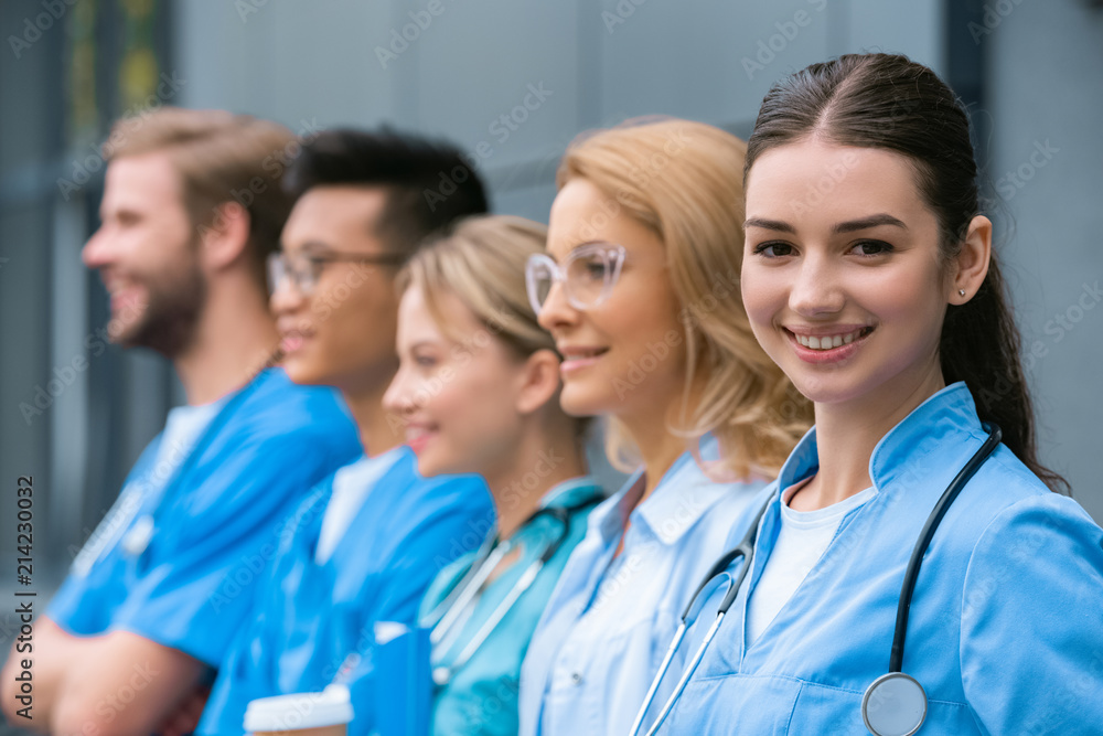 teacher and happy multicultural students standing in row near medical university teacher and happy multicultural students standing in row near medical university