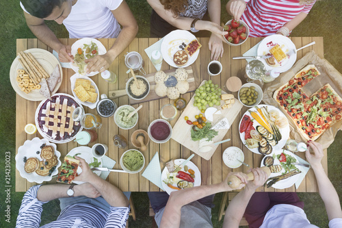 Top view on people eating lunch on wooden table in the garden