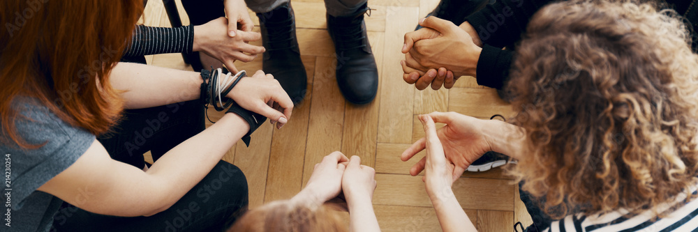 Tableau sur toile High angle view of hands of people in group therapy, talking and supporting each