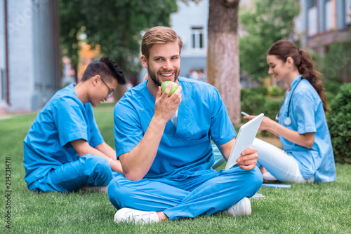 handsome caucasian medical student eating apple and holding tablet © LIGHTFIELD STUDIOS