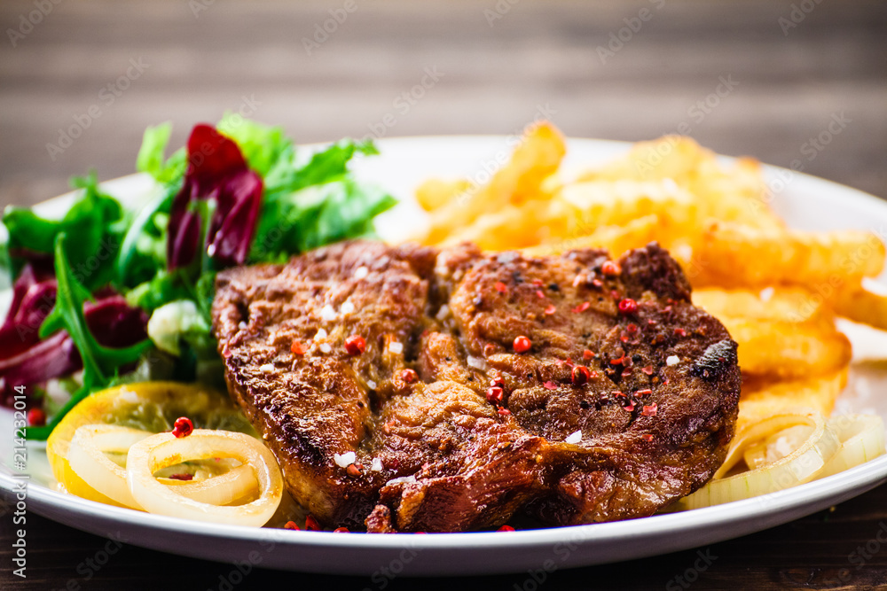 Grilled beefsteak with french fries and vegetable salad Grilled beefsteak with french fries and vegetable salad