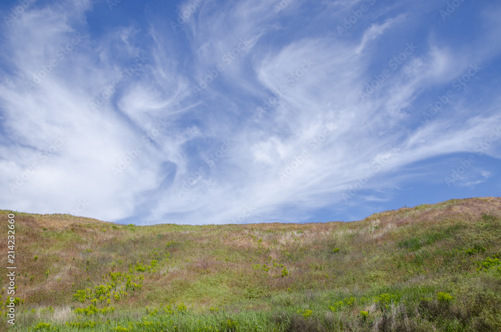 the top of a hill under the sky with clouds