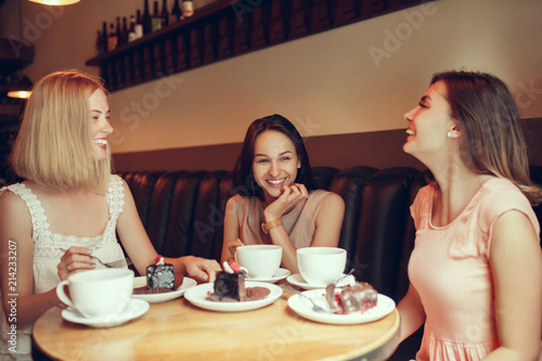 Two girl friends spend time together drinking coffee in the cafe, having breakfast and dessert.