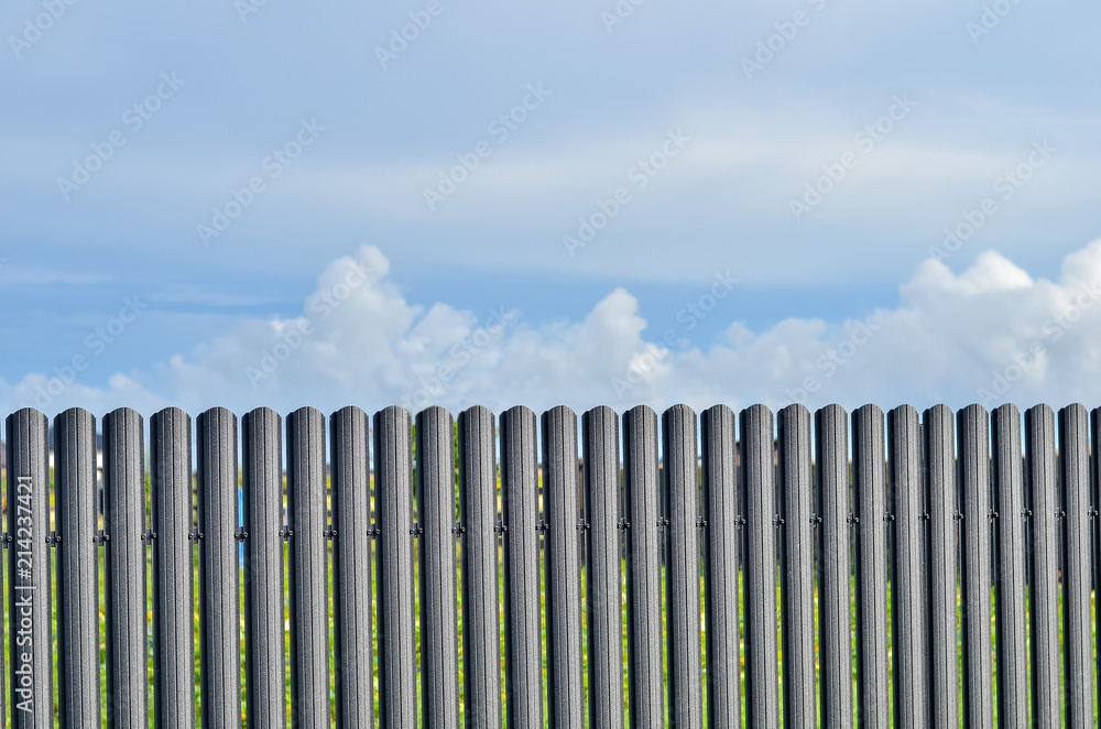 Fence pattern on background of transparent blue sky with clouds. Copy space.